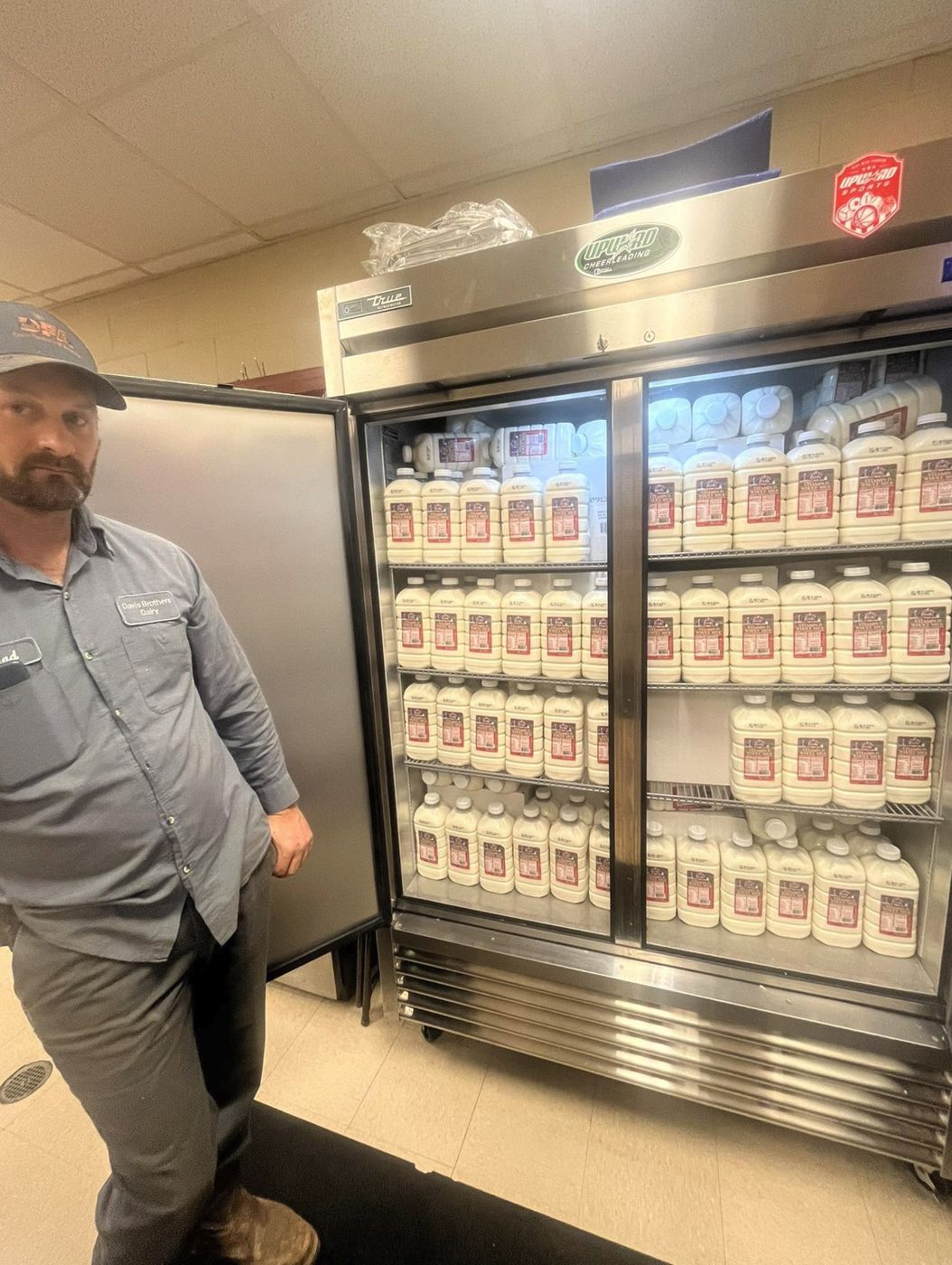 A Davis Brothers Dairy worker beside a full pantry fridge