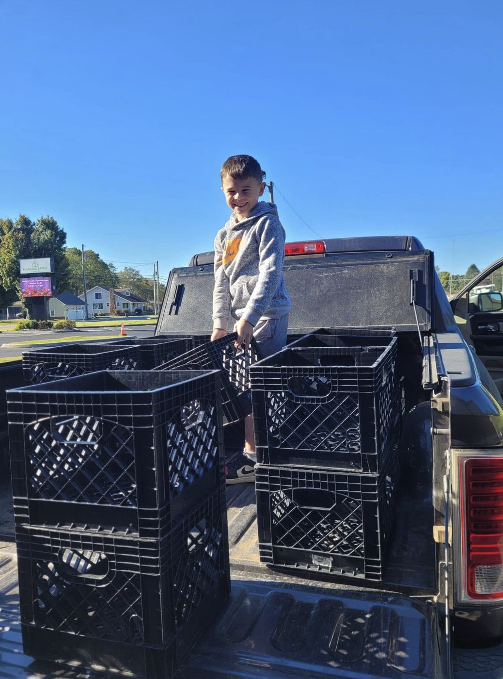A boy in a truck bed with empty milk crates