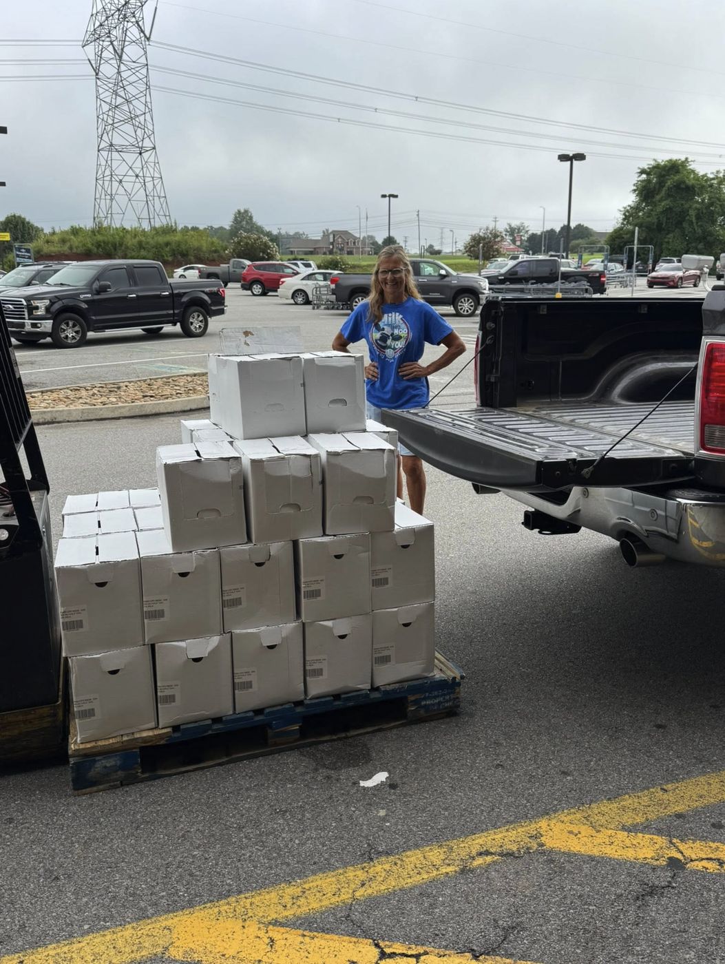 A volunteer next to a pallet of milk cases at a pickup