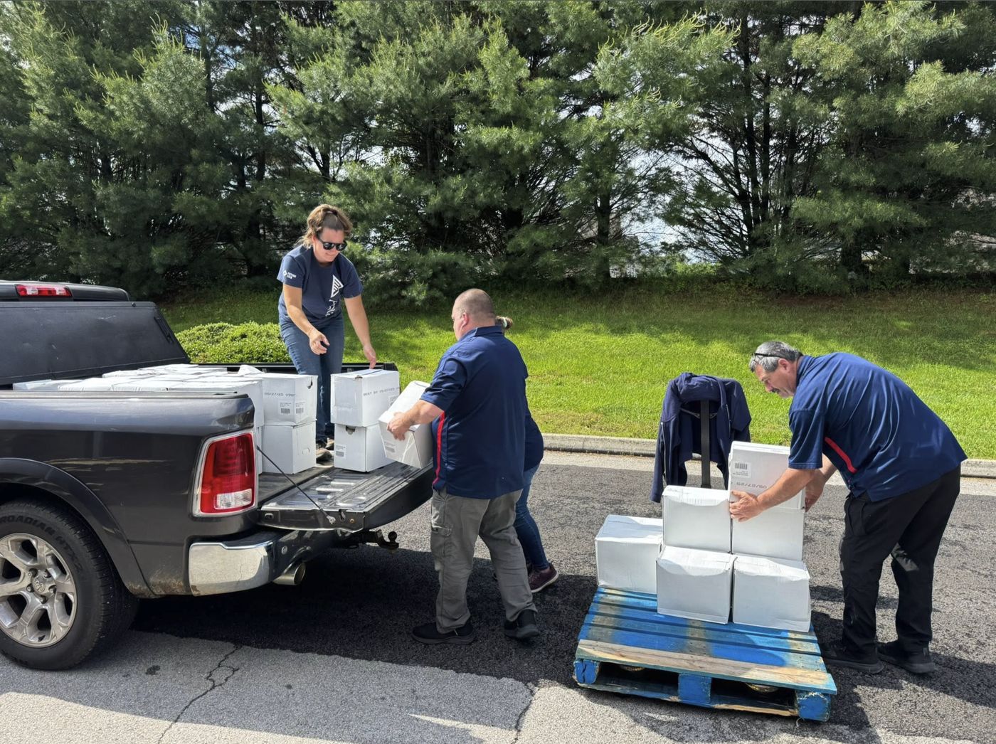 Volunteers unloading cases of milk from a pickup onto a pallet