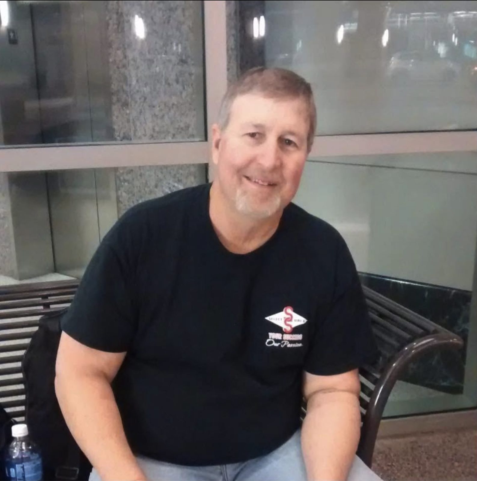 Randy Davis smiling, seated on a bench