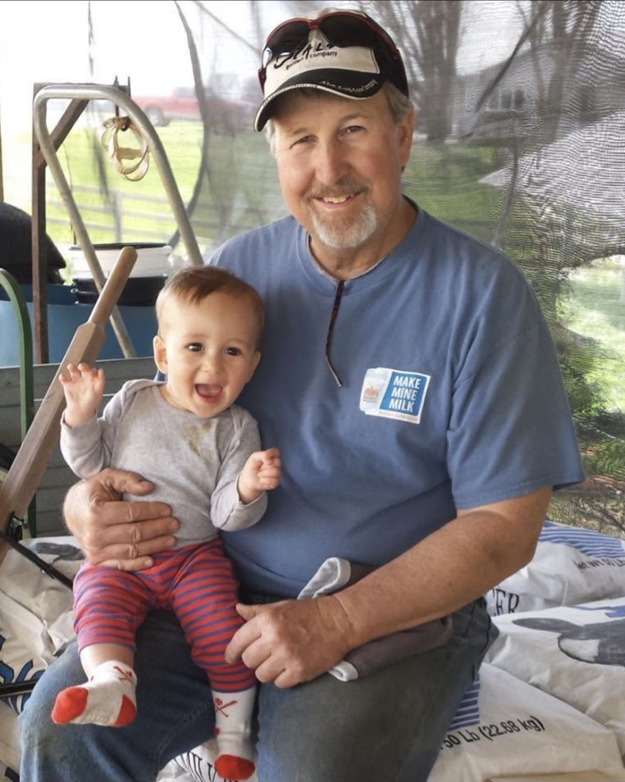 Randy Davis on the farm in a Make Mine Milk shirt, holding a grandchild on his lap
